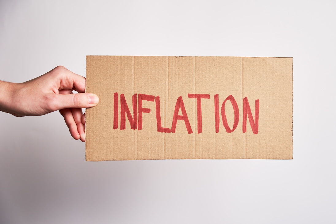 Hand die een kartonnen bordje vasthoust met daarop geschreven INFLATION