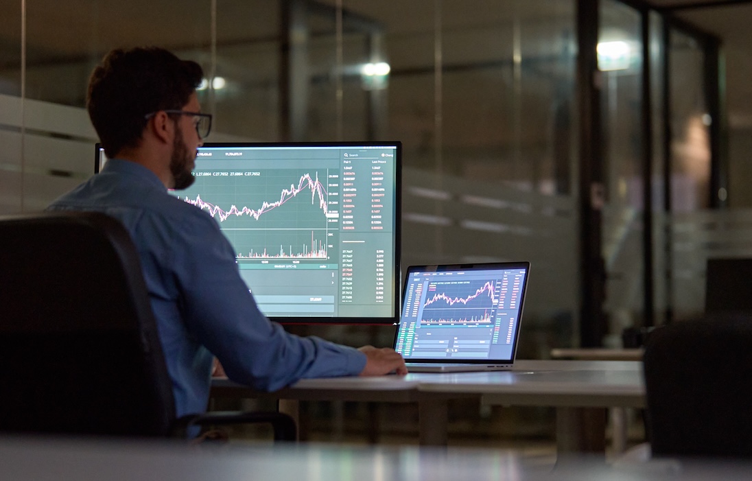 Man die kijkt naar scherm van laptop met daarop een sterk dalende grafiek