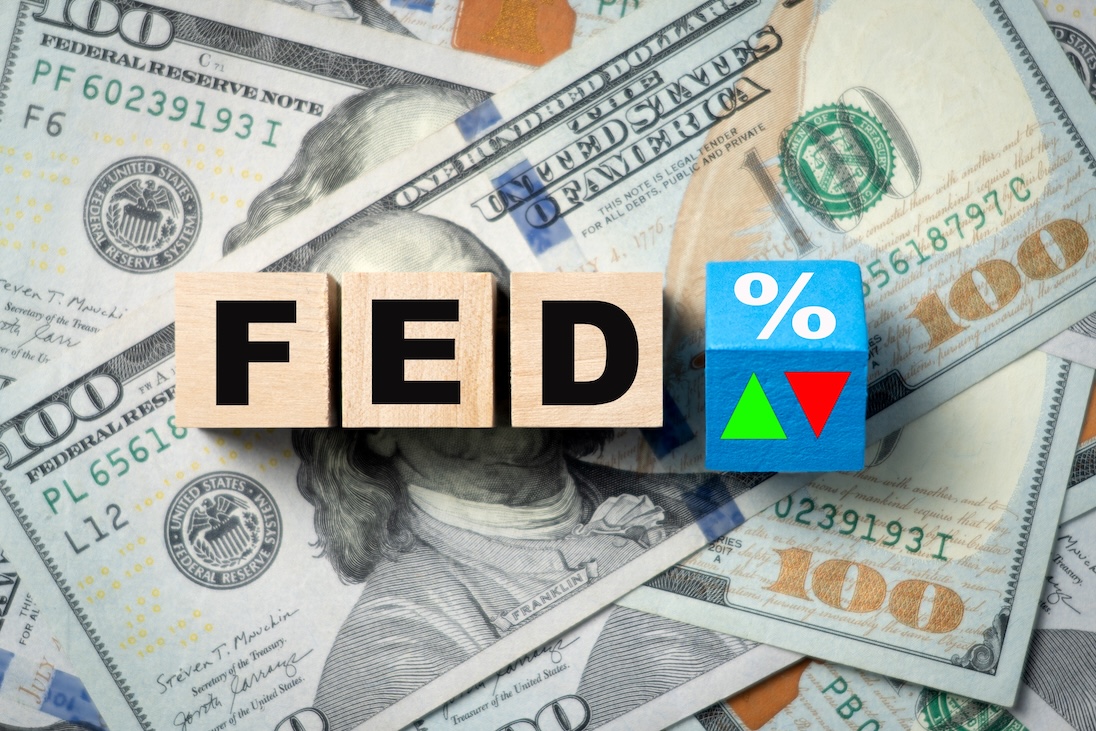 Op achtergrond dollarbiljetten waarop drie blokjes met letters F E D en een blokje met een %